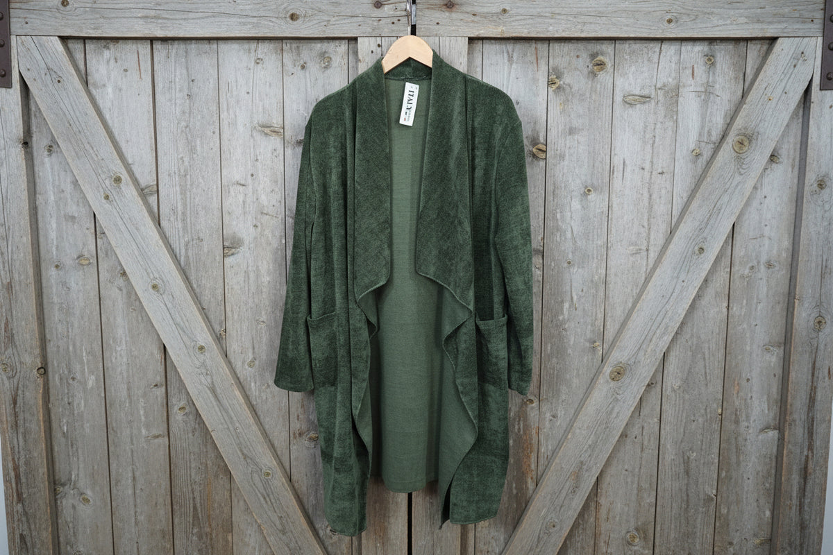 Green cardigan on a hanger against a striped wall