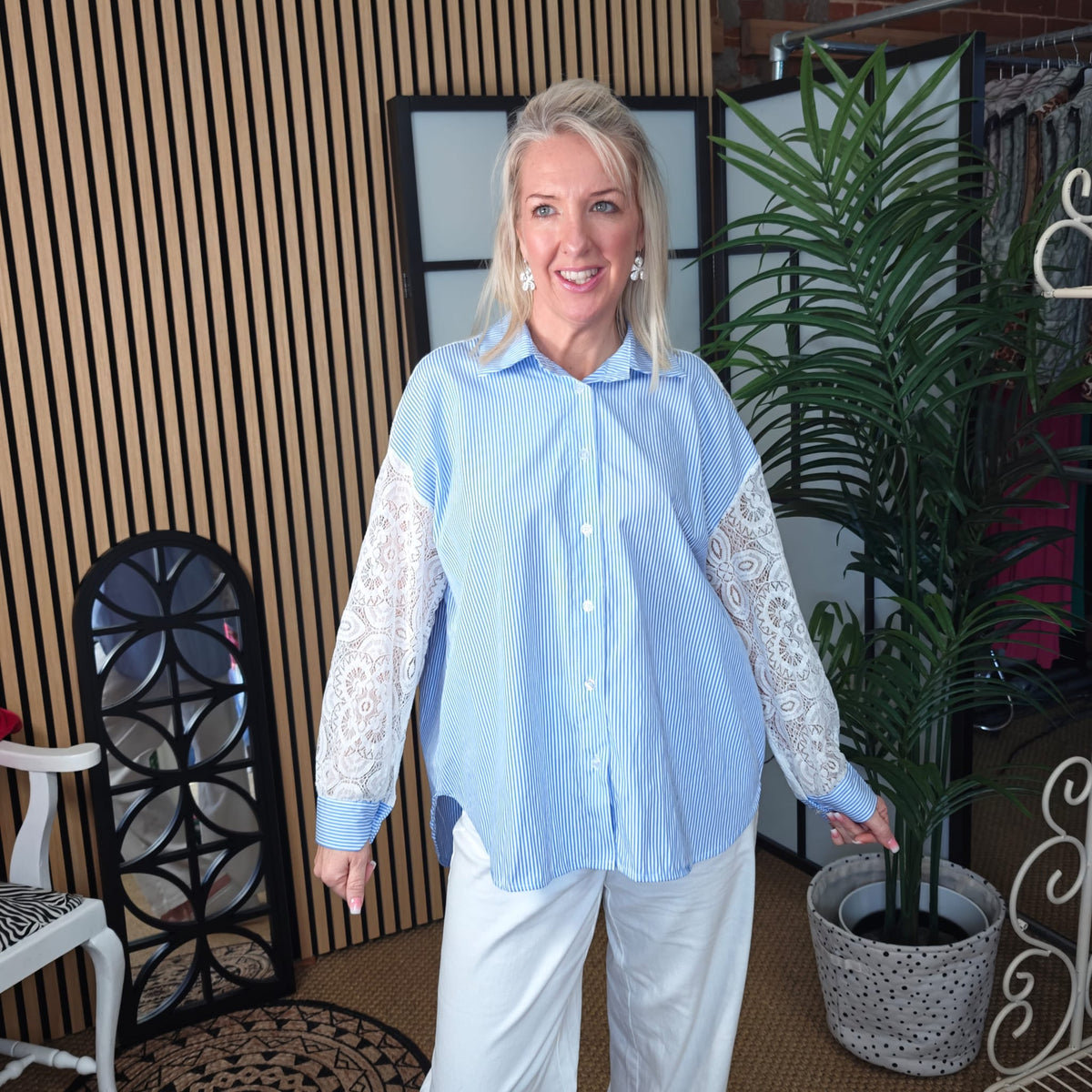 Woman wearing a light blue shirt with white lace sleeves in an indoor setting.