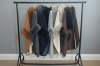 Collection of fur coats on a rack against a gray wall.