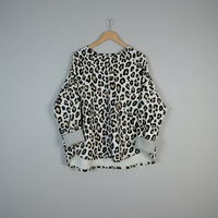 Leopard print top on a hanger against a plain background