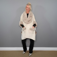 Woman wearing a white coat with fur collar against a gray wall