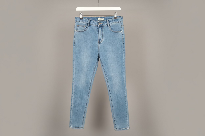 Light blue jeans on a hanger against a gray background