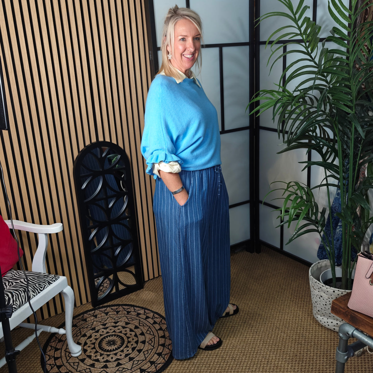 Woman in a blue outfit standing in a room with decor elements.