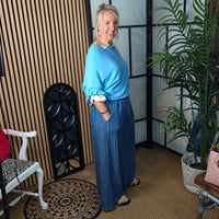 Woman in a blue outfit standing in a room with decor elements.