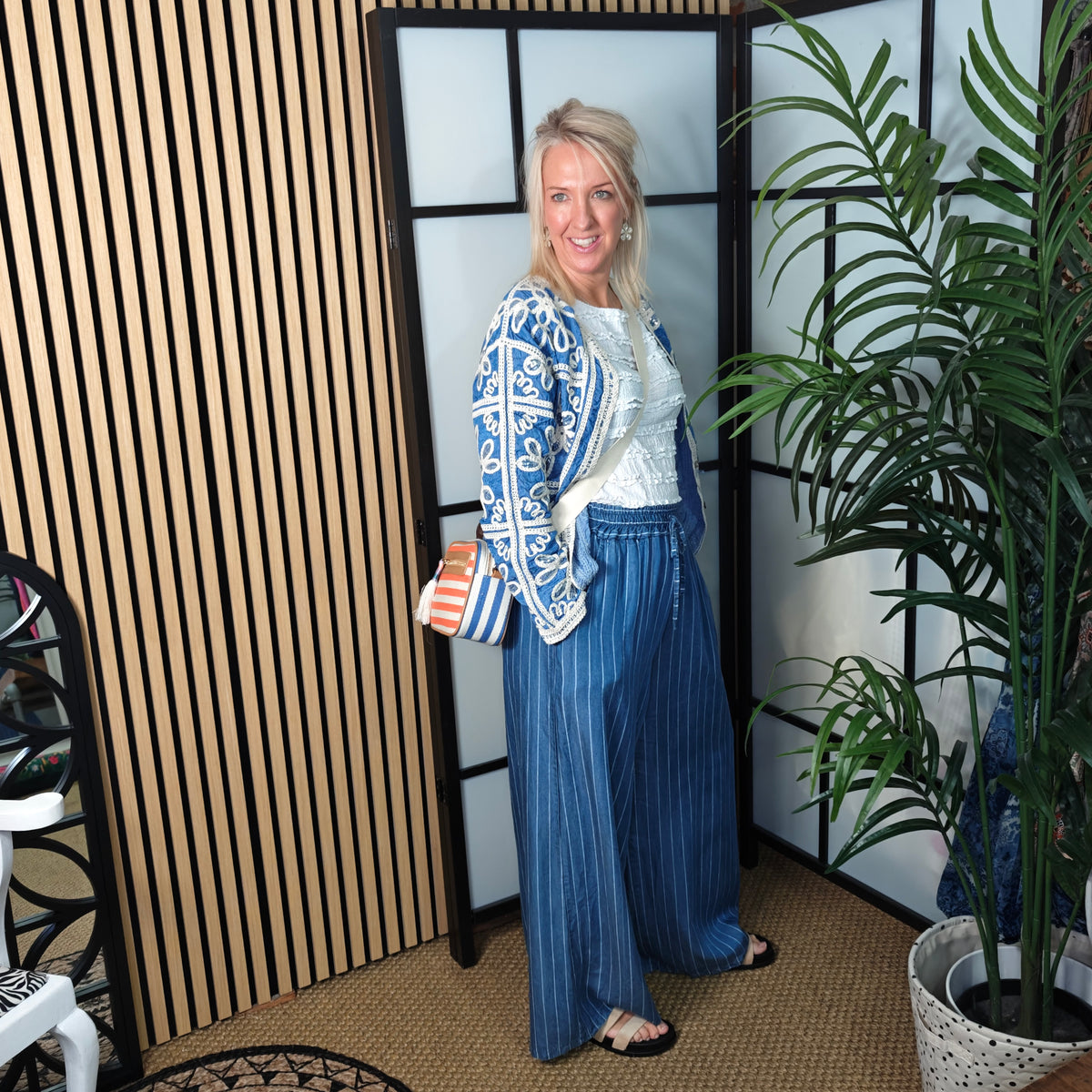 Woman in a stylish outfit standing in a room with decorative elements