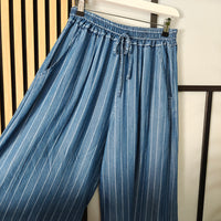 Blue striped pants hanging on a rack against a neutral background