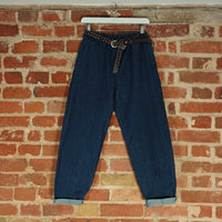 Blue jeans with a belt hanging against a brick wall