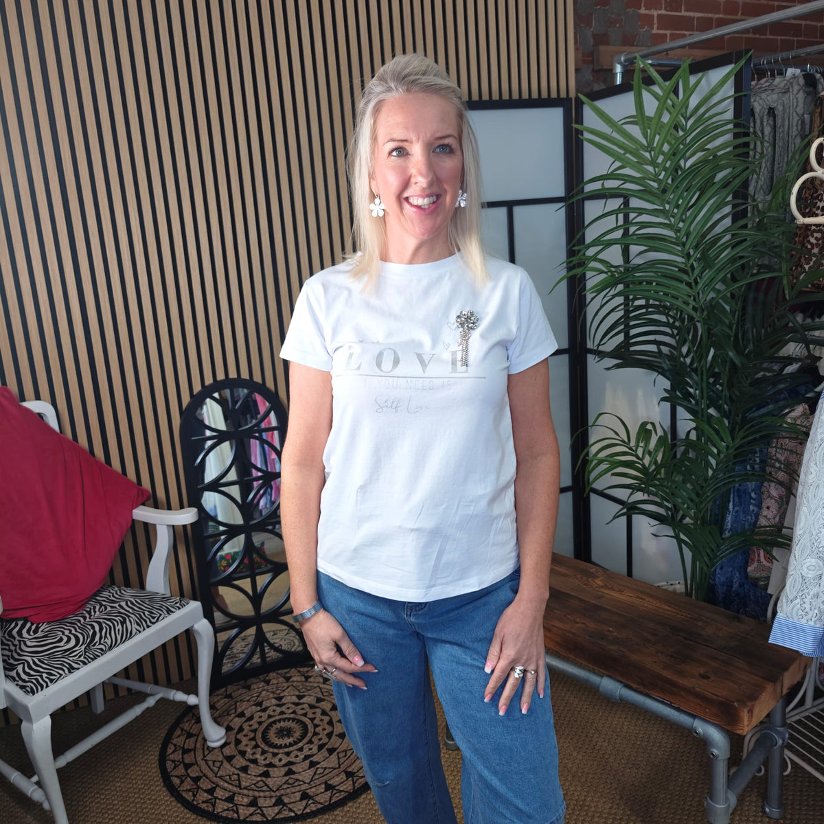 Woman wearing a white t-shirt with a logo in a casual indoor setting